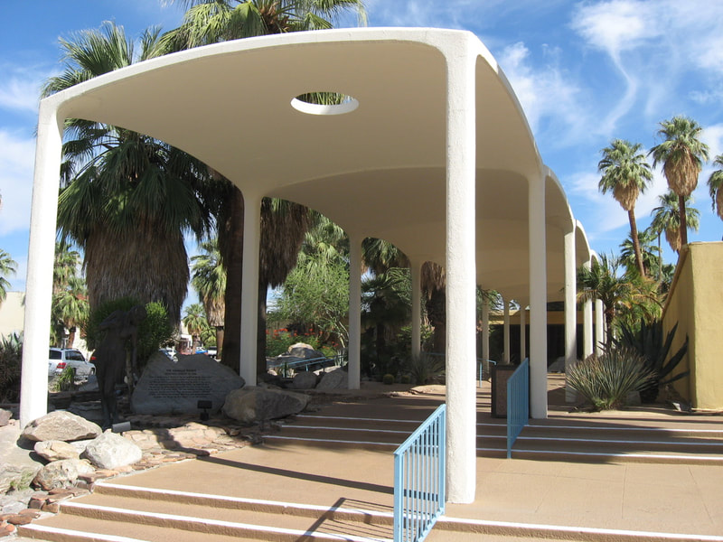 Midcentury modern entrance to Palm Springs Colonnade & Spa Resort with palm trees and steps in Palm Springs